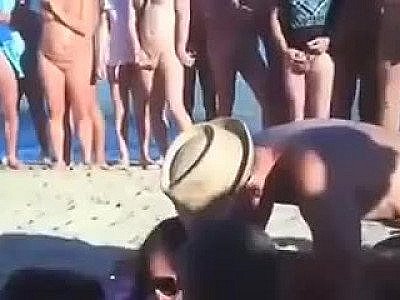 Two women suck a guy on a nudist beach